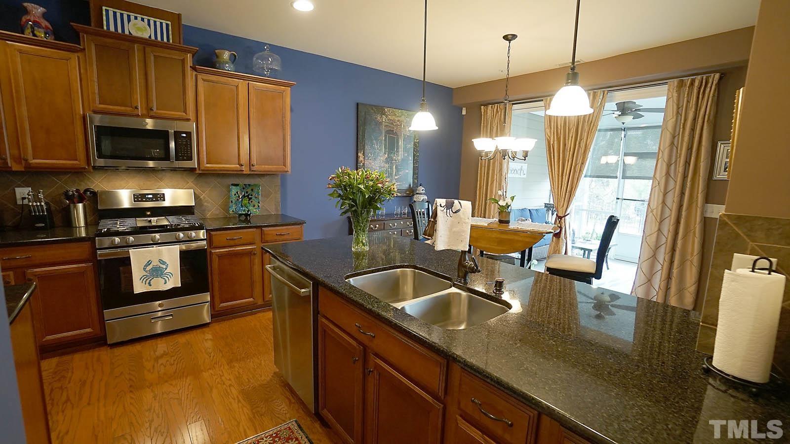 10115 Barnhart Way Raleigh, NC 27617 - Photo 22 of 60 a kitchen with stainless steel appliances a sink a stove a microwave a sink a refrigerator white cabinets and wooden floor
