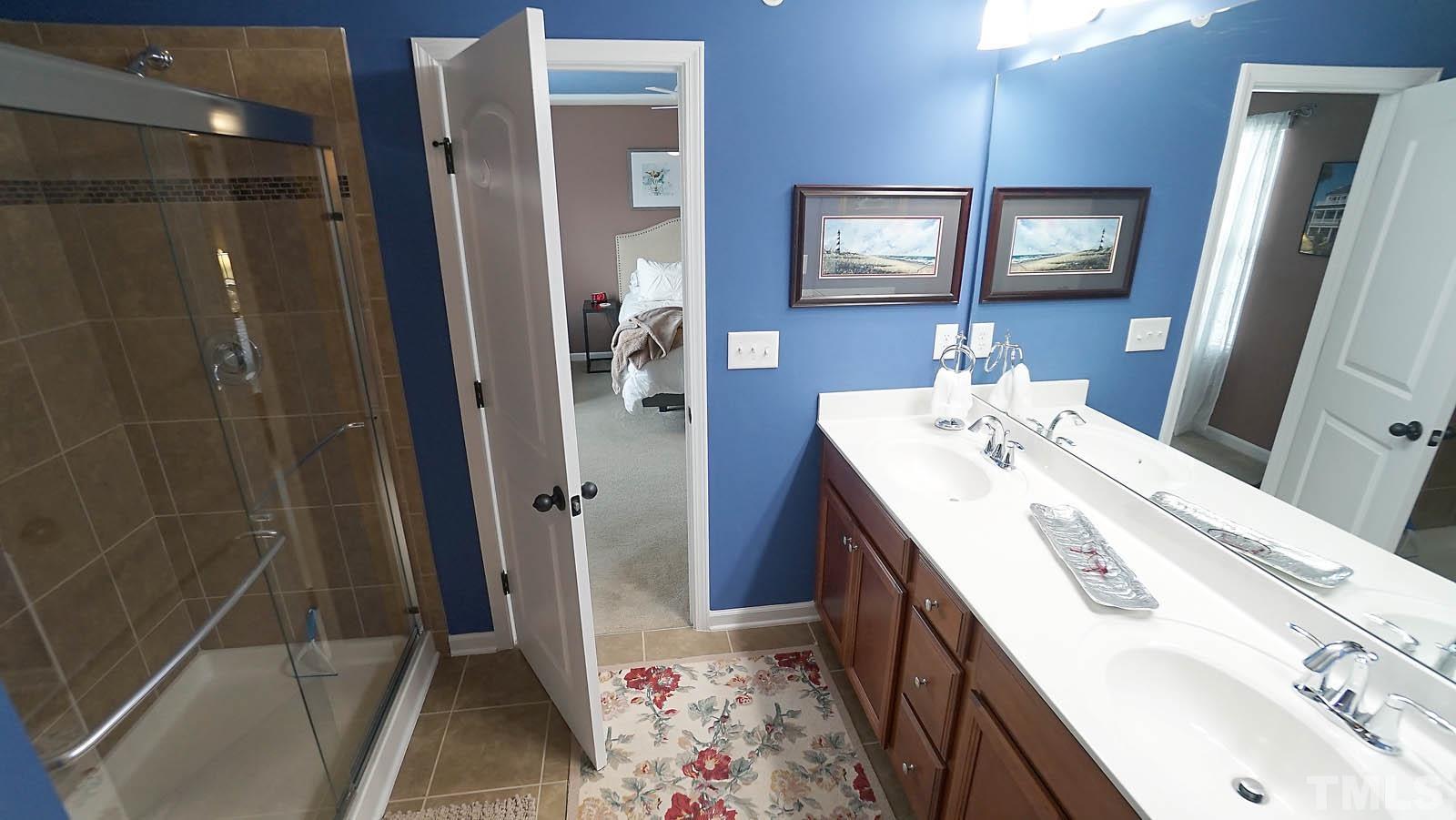 10115 Barnhart Way Raleigh, NC 27617 - Photo 46 of 60 a en suite bathroom with a double vanity sink a mirror and a shower
