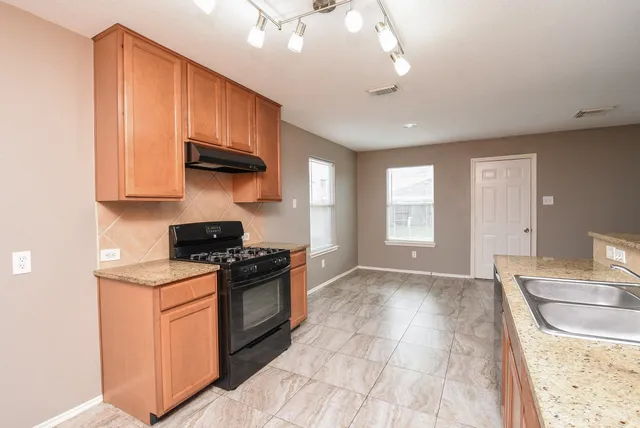 a kitchen with stainless steel appliances granite countertop a stove a sink and a microwave