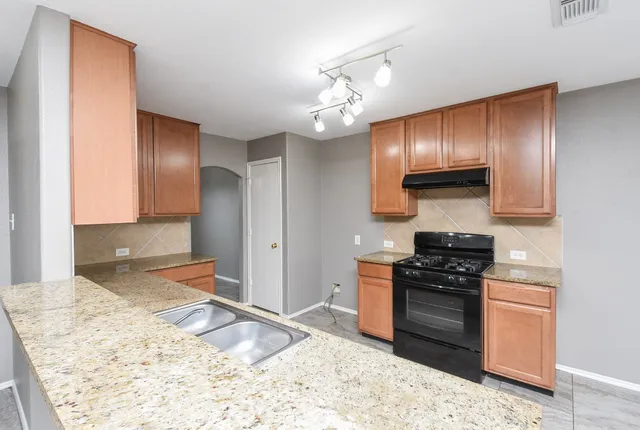a kitchen with granite countertop stainless steel appliances and wooden cabinets