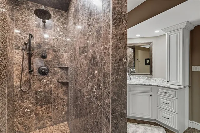 a bathroom with a granite countertop sink a mirror and shower