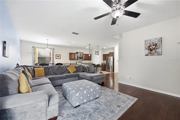 a open kitchen with stainless steel appliances granite countertop a stove top oven a sink dishwasher a dining table and chairs with wooden floor