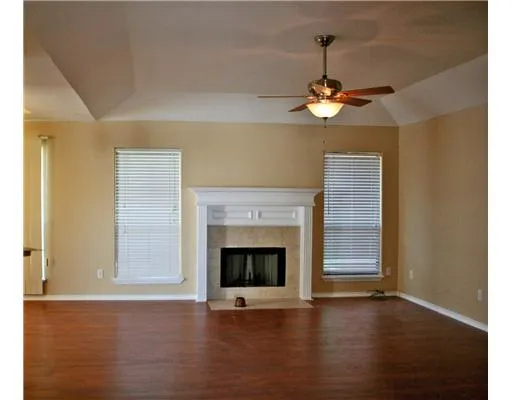 a view of an empty room with wooden floor fireplace and a window