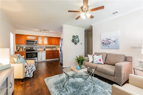 a living room with furniture kitchen view and a chandelier