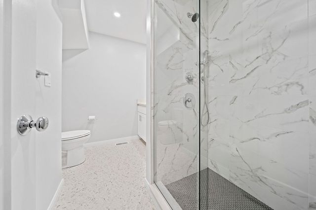 a bathroom with a granite countertop shower and a toilet