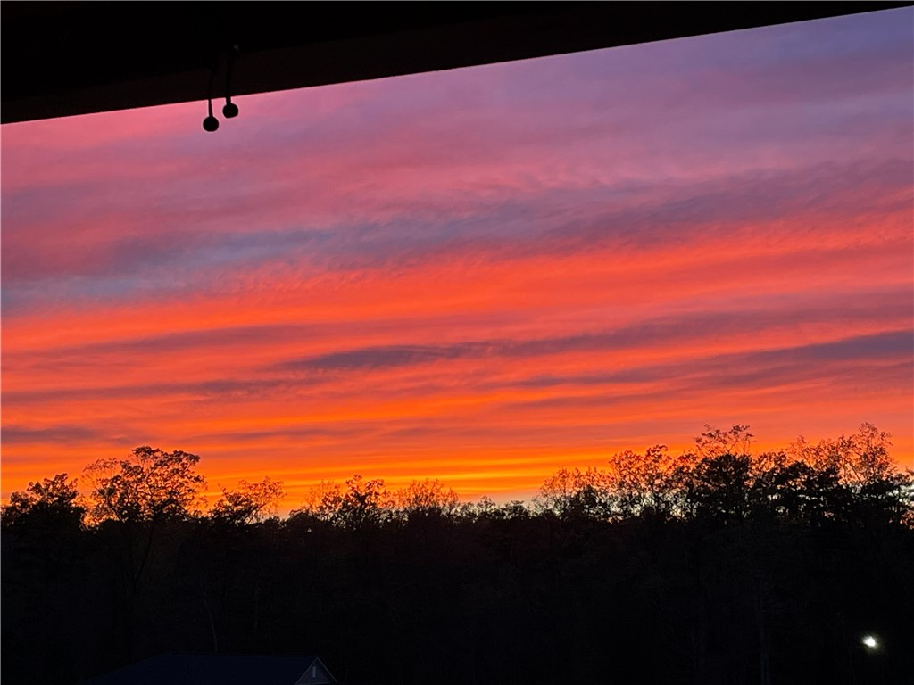 412 Chadwick Lane Walhalla, SC 29691 - Photo 36 of 37 Witness an awe-inspiring vista as the evening sky erupts in fiery hues above a tranquil tree line.