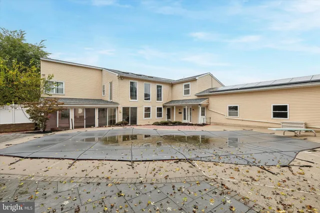 a view of a white house next to a yard with large trees