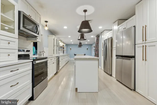 a kitchen with stainless steel appliances kitchen island a refrigerator oven a sink dishwasher and white cabinets next to a window