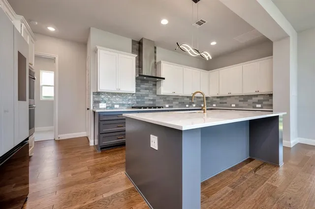 a kitchen with stainless steel appliances granite countertop a sink dishwasher a stove and a refrigerator with wooden floor