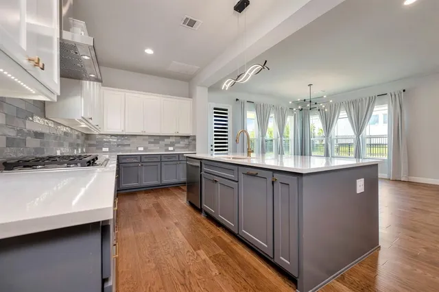 a large kitchen with a large window a sink stainless steel appliances and cabinets