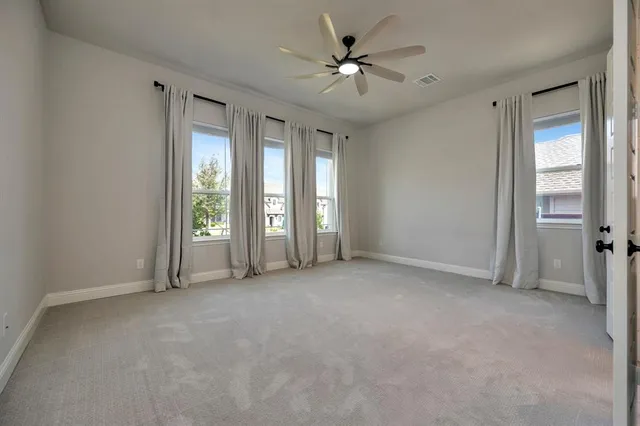 an empty room with windows and fan