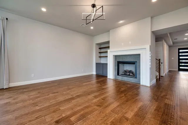 a view of an empty room with wooden floor fireplace and a window