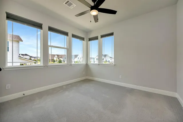 an empty room with windows and ceiling fan