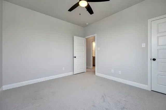 an empty room with chandelier fan and closet area