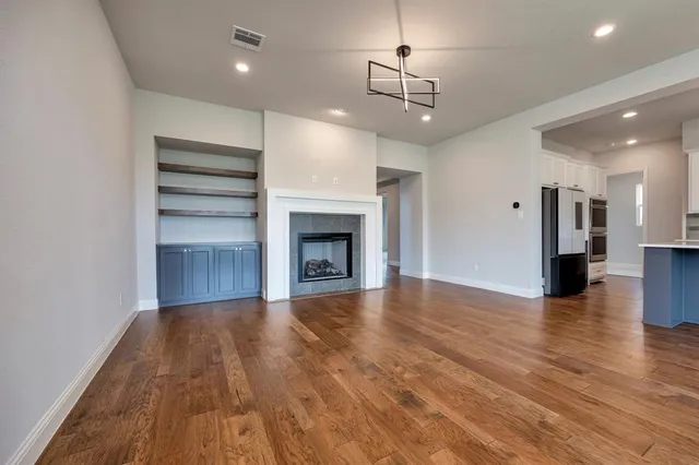 a view of an empty room with wooden floor fireplace and a window