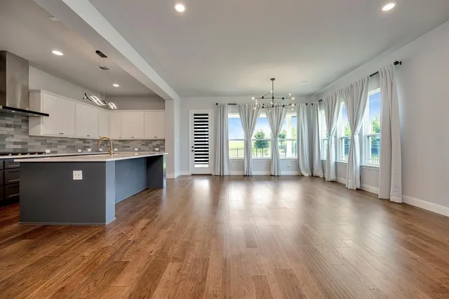 a view of a kitchen with a fridge and wooden floor