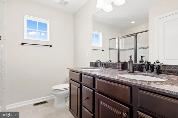 a bathroom with a granite countertop toilet sink and mirror