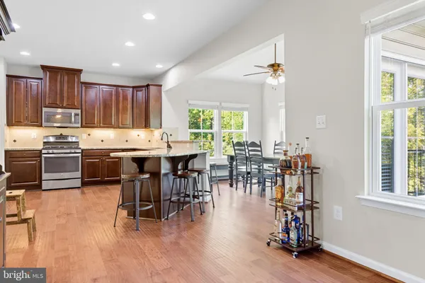 a kitchen with stainless steel appliances a dining table chairs and a white refrigerator with a large window