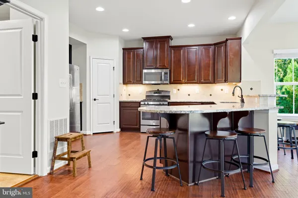 a kitchen with kitchen island granite countertop wooden floors and white stainless steel appliances