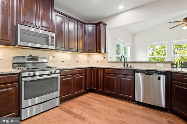a kitchen with stainless steel appliances granite countertop wooden cabinets a sink and a stove