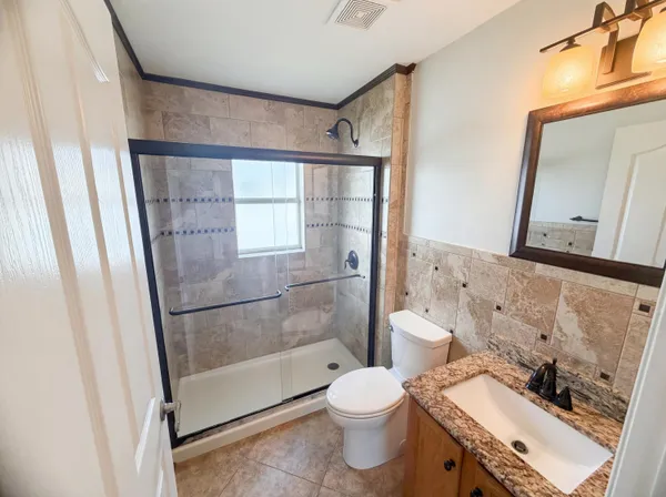 a bathroom with a granite countertop sink toilet and shower