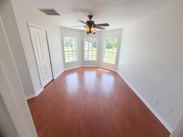 a view of an empty room with wooden floor and a window