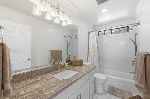 a bathroom with a granite countertop sink toilet and shower
