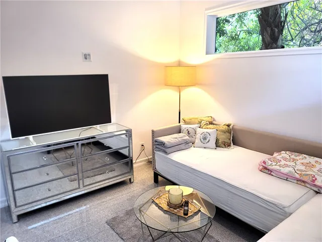 a living room with a bed furniture and a flat screen tv