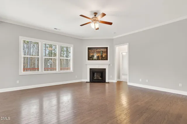 a view of a livingroom with a fireplace a ceiling fan and wooden floor