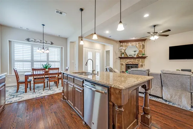 a kitchen with stainless steel appliances granite countertop a stove a refrigerator a oven a sink with island and chairs with wooden floor