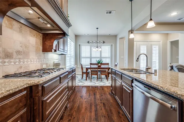a kitchen with stainless steel appliances granite countertop a stove a refrigerator a kitchen island a sink and chairs