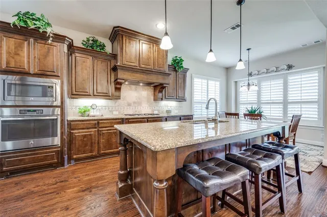 a kitchen with granite countertop a table chairs stainless steel appliances and cabinets