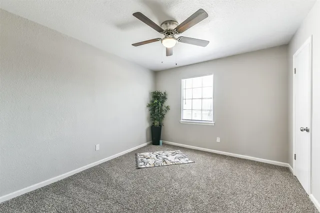 an empty room with windows and ceiling fan