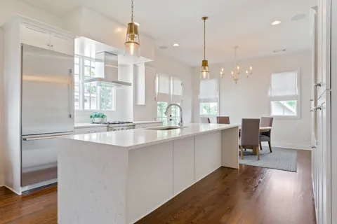a room with kitchen island granite countertop a sink cabinets and wooden floor