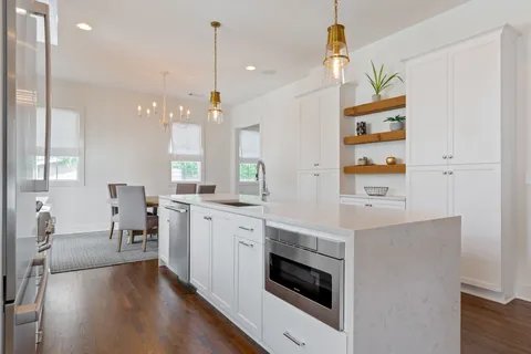 a kitchen with stainless steel appliances a stove a sink and white cabinets with wooden floor