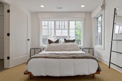 a bed sitting in a spacious bedroom next to a window