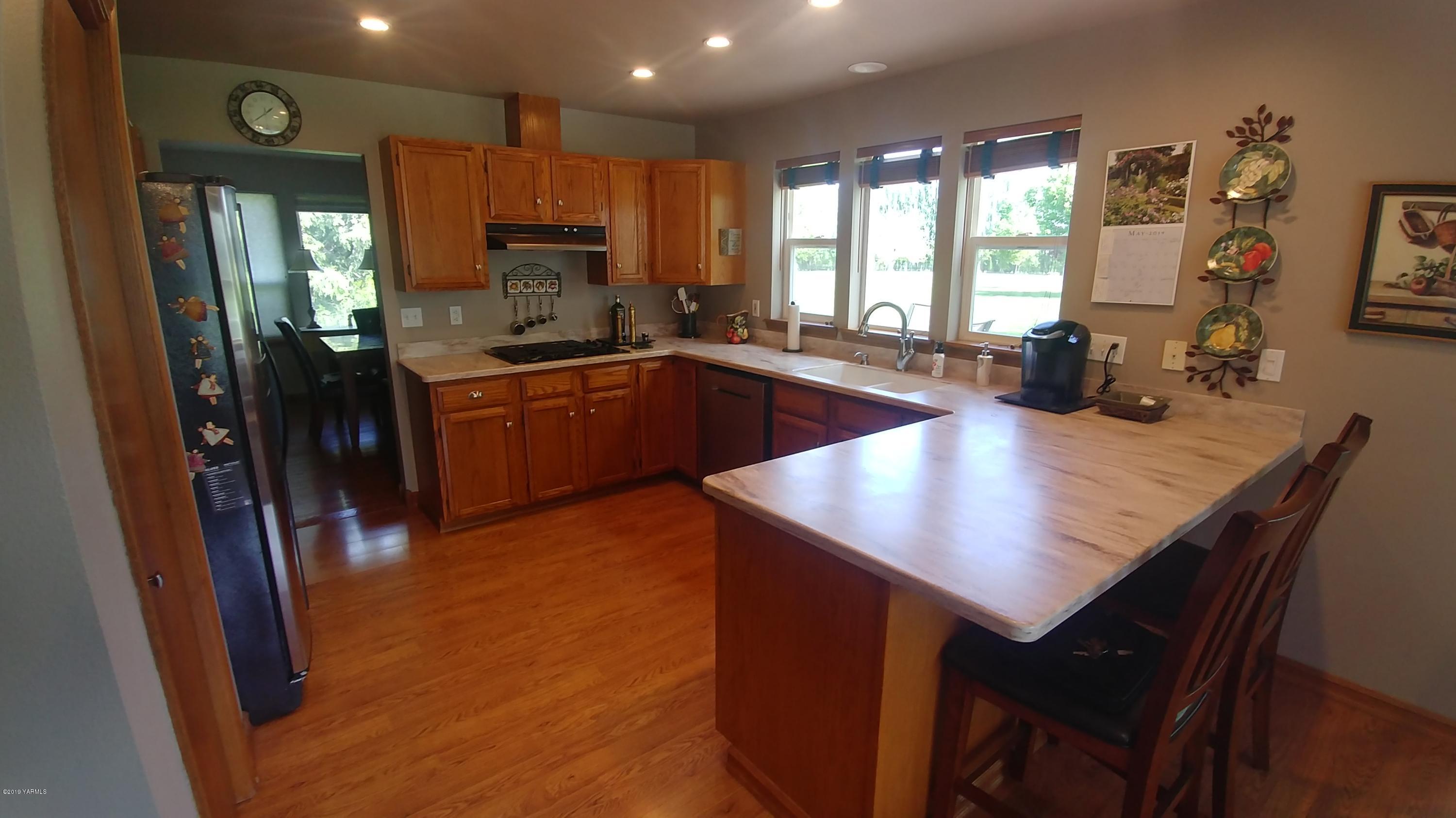 2001 Moore Road Yakima, WA 98908 - Photo 7 of 36 a kitchen with a refrigerator a sink dishwasher a stove and a dining table with wooden floor