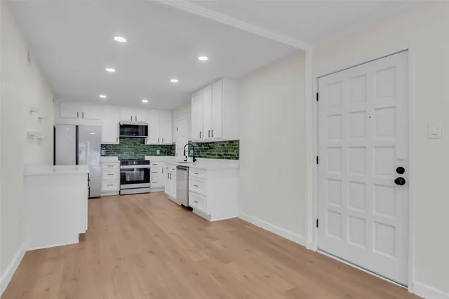 a kitchen with white cabinets and stainless steel appliances