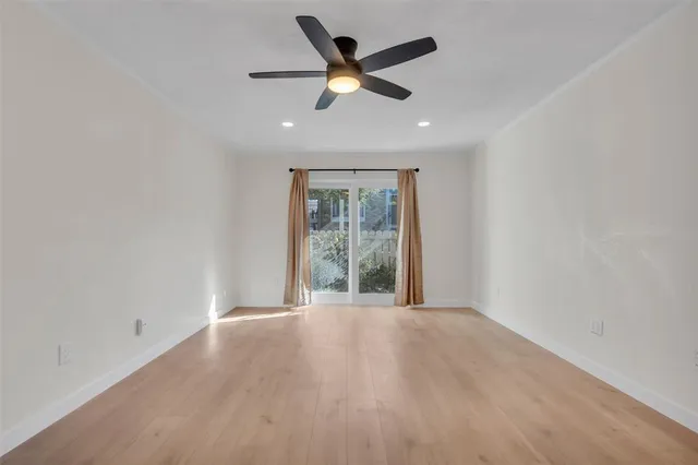 an empty room with ceiling fan and windows
