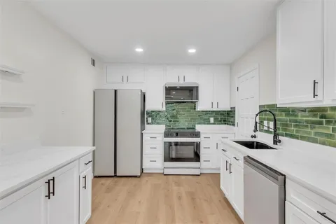 a kitchen with a sink a refrigerator a stove top oven and cabinets