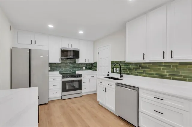 a kitchen with granite countertop white cabinets and stainless steel appliances