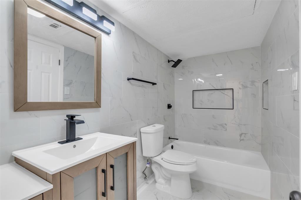 6077 Milton Street, Unit 137 Dallas, TX 75206 - Photo 8 of 15 a bathroom with a toilet a sink a mirror and vanity