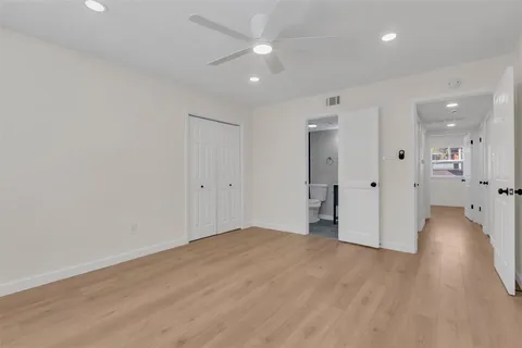 an empty room with wooden floor and a ceiling fan