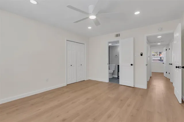 an empty room with wooden floor and a ceiling fan