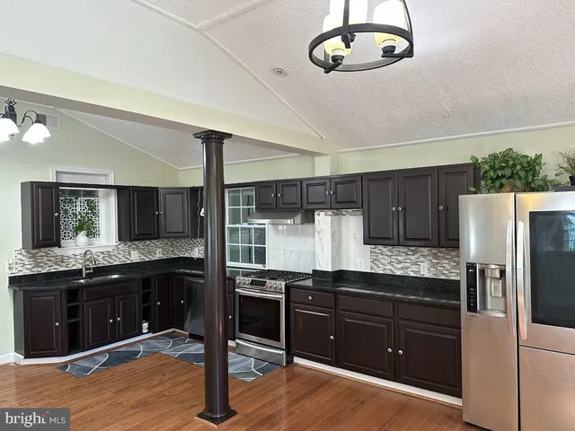 a kitchen with granite countertop a refrigerator and a stove top oven