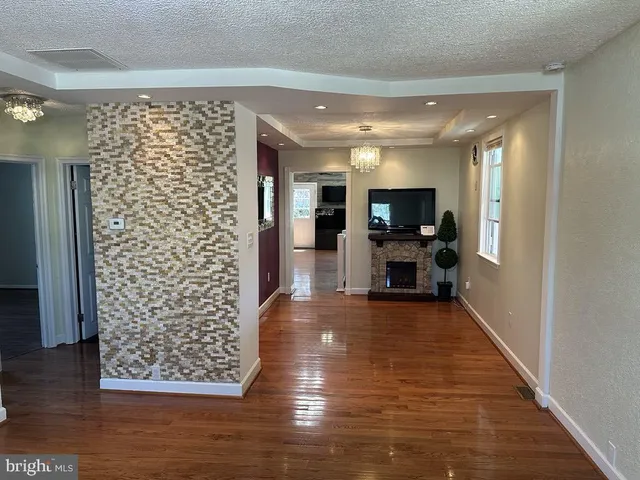 a view of a hallway with wooden floor and a flat screen tv