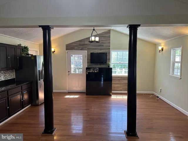 a view of a hallway view with wooden floor and a living room
