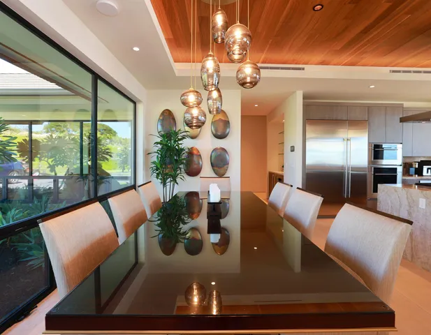 a view of a dining room with furniture a chandelier and large windows