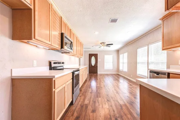 a kitchen with stainless steel appliances granite countertop a stove a sink and white cabinets with wooden floor