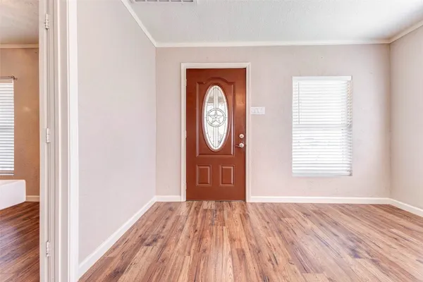 a view of an empty room with window and wooden floor